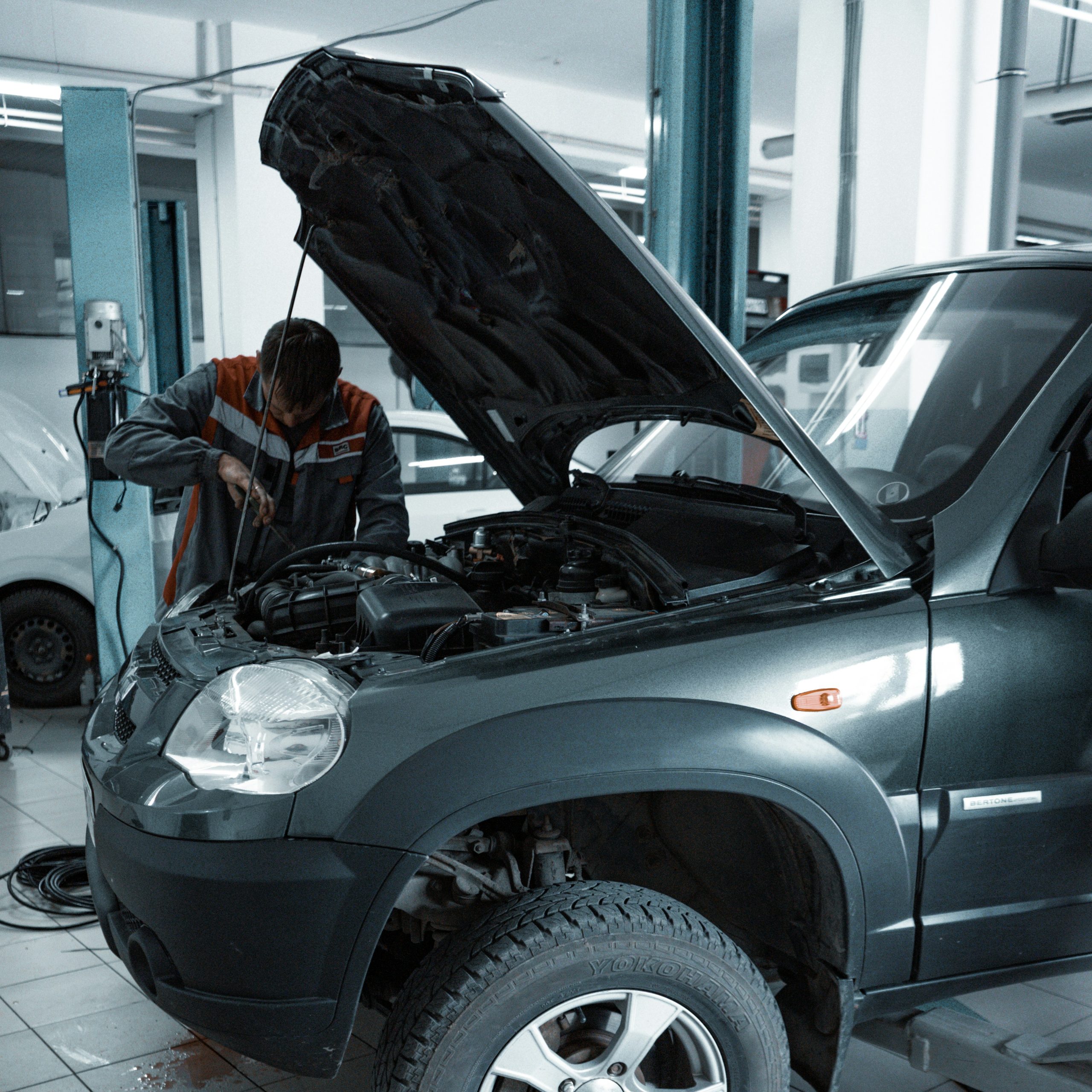Worker doing car servicing on car with hood open